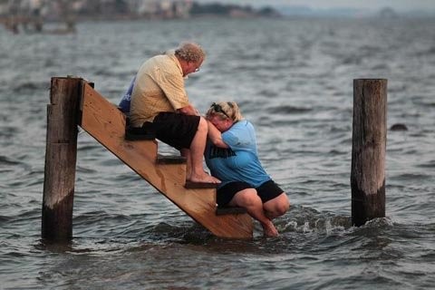 9. Ông Billy Stinson và con gái ngồi ngẩn ngơ trên bậc thềm còn sót lại của ngôi nhà bị nước cuốn trôi sau trận bão Irene quét qua bắc Carolina (Mỹ) vào hồi tháng 8 vừa qua. (Ảnh: Getty Images)